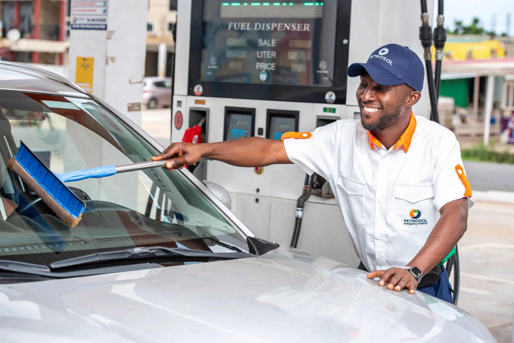 A PETROSOL forecourt attendant cleaning a customer's windscreen while their car refuels