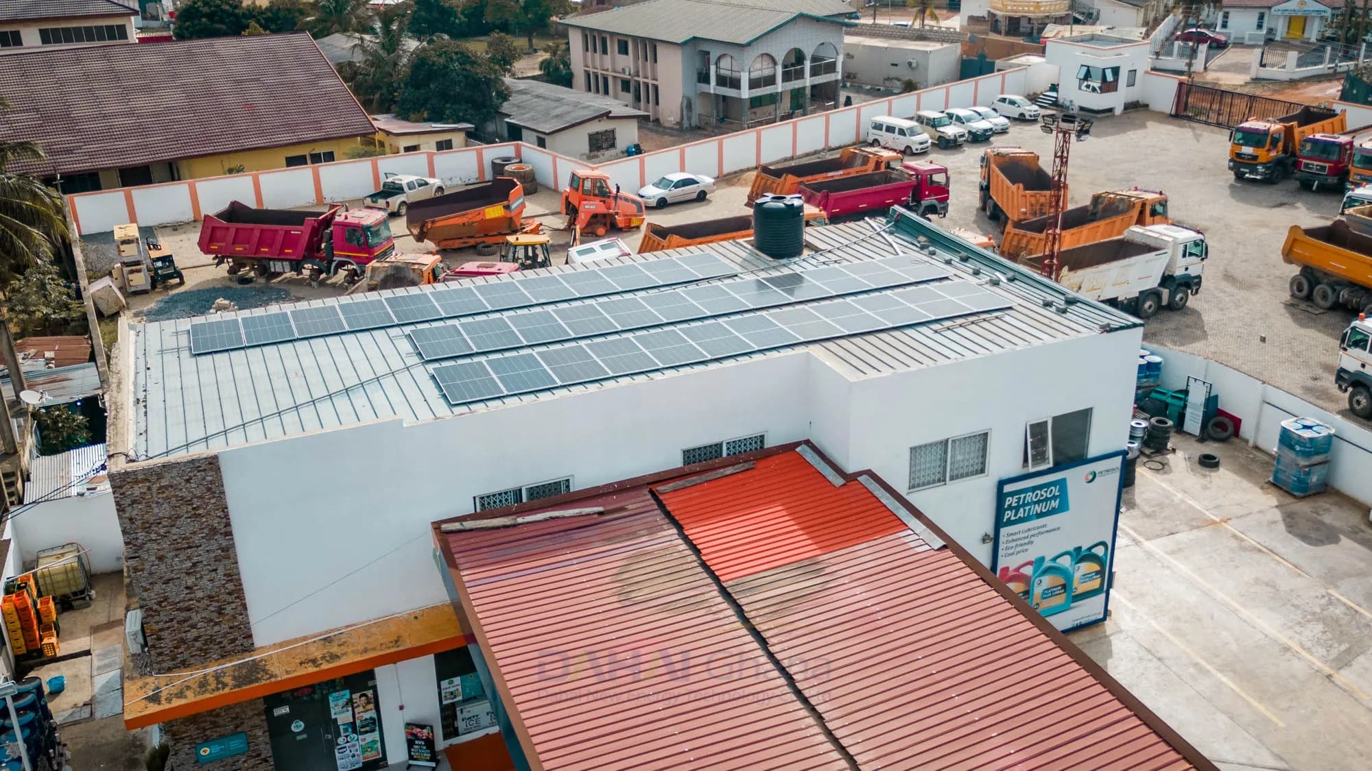 Solar array on a PETROSOL station roof, with the Platinum lubricants billboard and a haulage yard beyond it