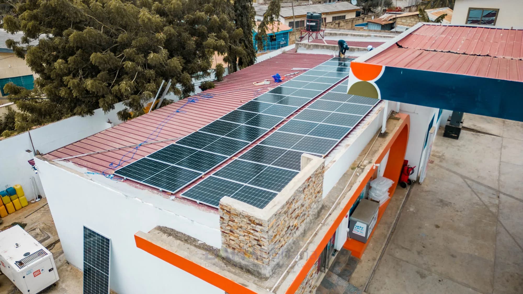 Aerial view of solar panels covering the roof of a PETROSOL station beside its orange and navy forecourt canopy